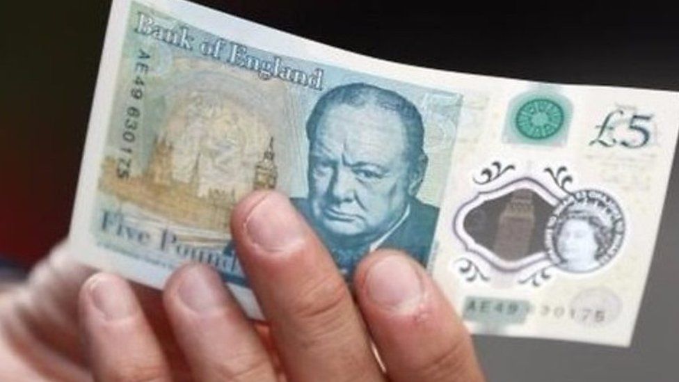 Someone holding £5 note