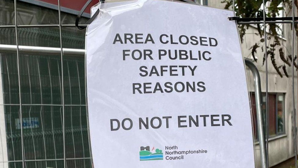 "Area closed" notice on metal fencing surrounding new building