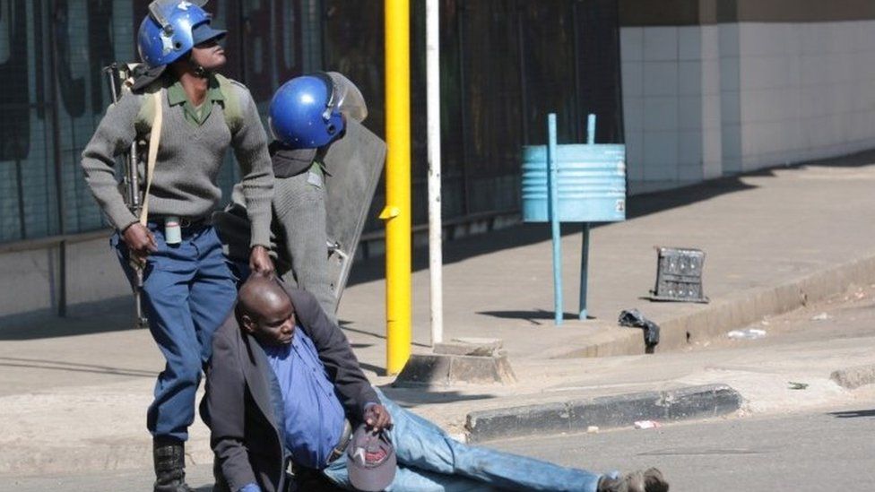 Police drag away protester as they disperse crowds in Harare - 16 August