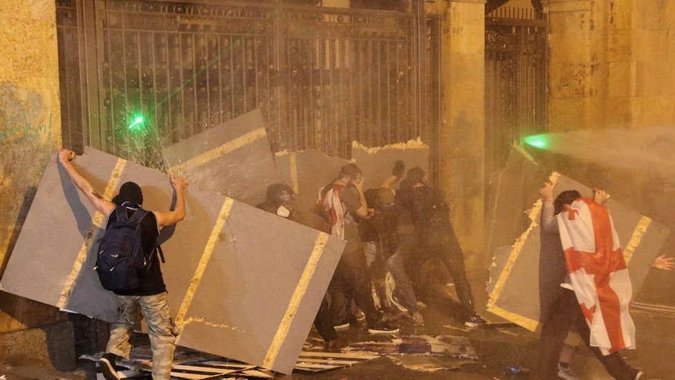 Protesters strike the entrance of Parliament as water cannons are used to disperse them during a rally against a bill on "foreign agents", in Tbilisi on 1 May