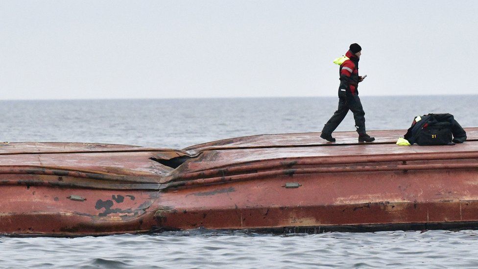 A sea rescue member walks over the hull of the capsized Danish cargo ship Karin Hoej after it collided with the British cargo ship Scot Carrier in the Baltic Sea