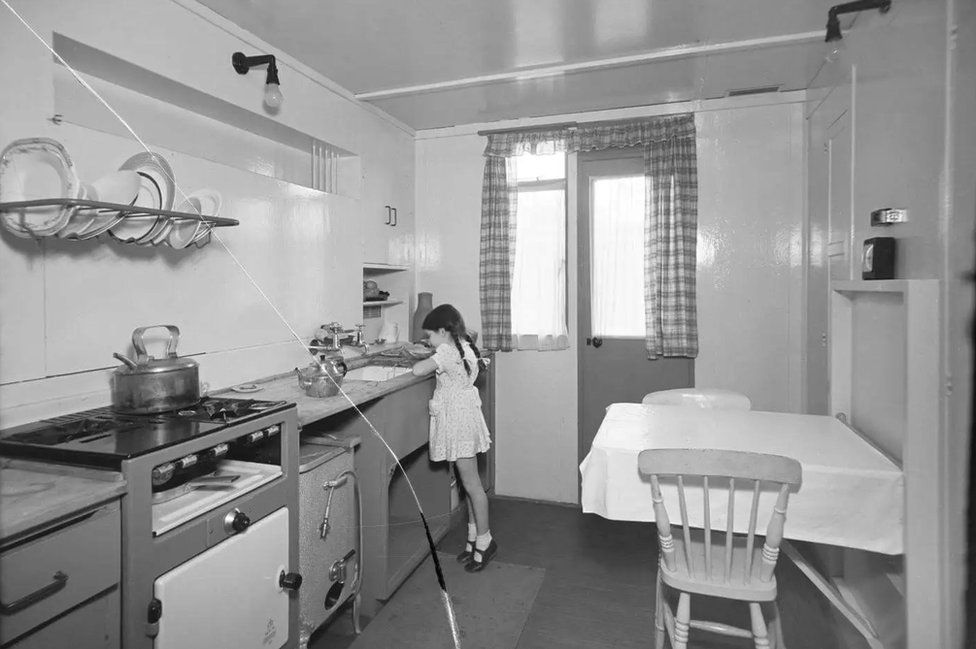 A young girl in the kitchen of a Uni-Seco prefabricated home in Brixton, London
