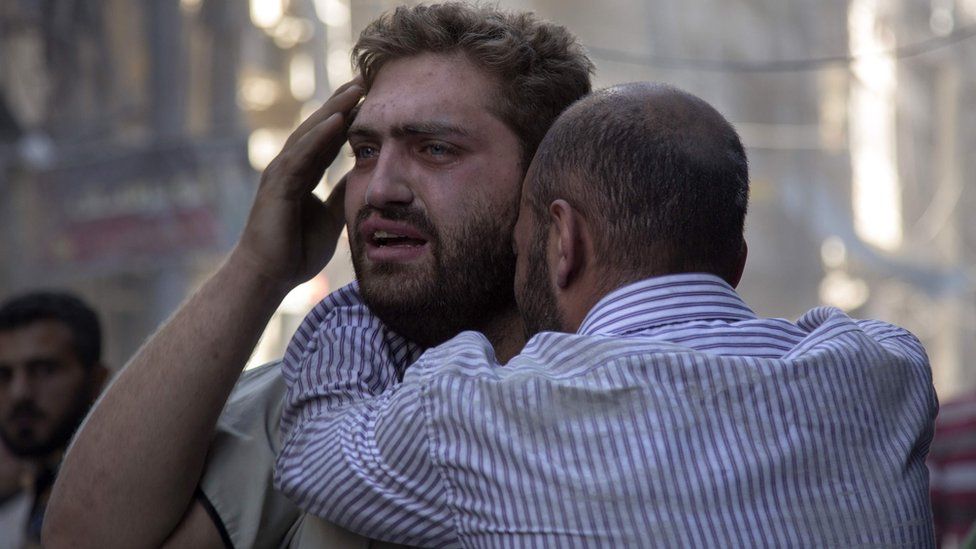 Syrians react as the bodies of children are pulled from the rubble of a building following air strikes in the rebel-held area of Aleppo on 27 September