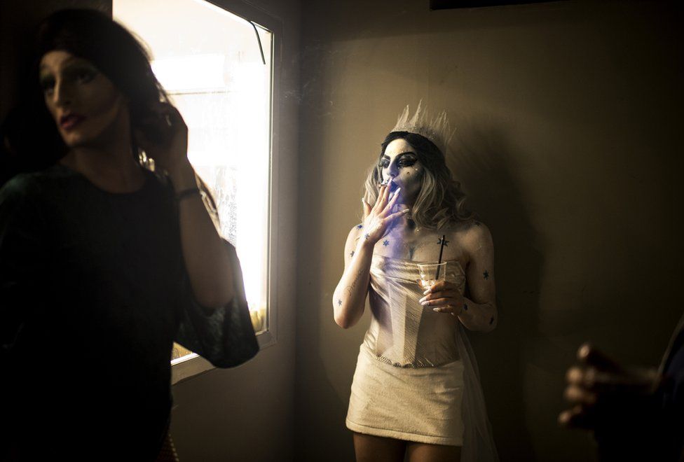 Elias dressed as drag queen Melanie Coxxx takes a cigarette break