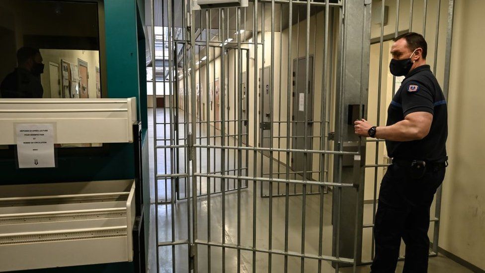 Prison guard closing a gate in a corridor at the Prison de la Santé in Paris