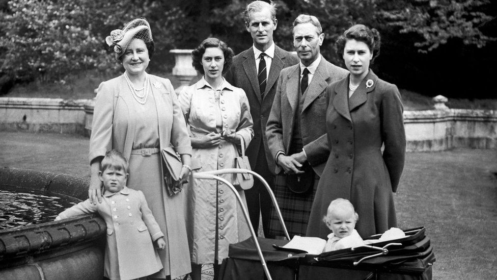 Prince Charles, dangling his hand in an ornamental pond, The Queen, Princess Margaret, The Duke of Edinburgh, King George VI, Princess Elizabeth and Princess Anne, in a pram, on holiday at Balmoral. 21/08/1951