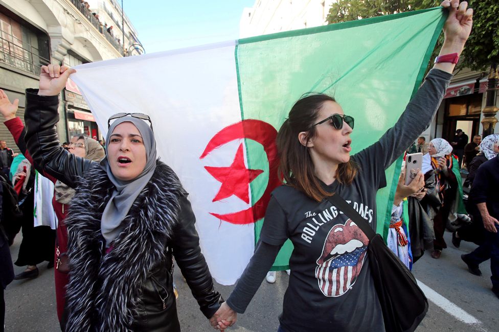 Women carry a national flag during a march in Algiers, Algeria - Sunday 8 March 2020