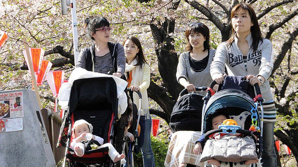 Young mothers push baby carriages s alongside a river in Tokyo on a sunny spring day