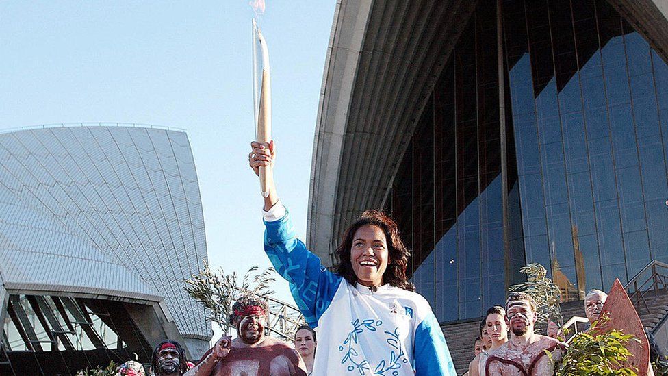 Olympic sprinter Cathy Freeman holds the Olympic torch at the Sydney Opera House