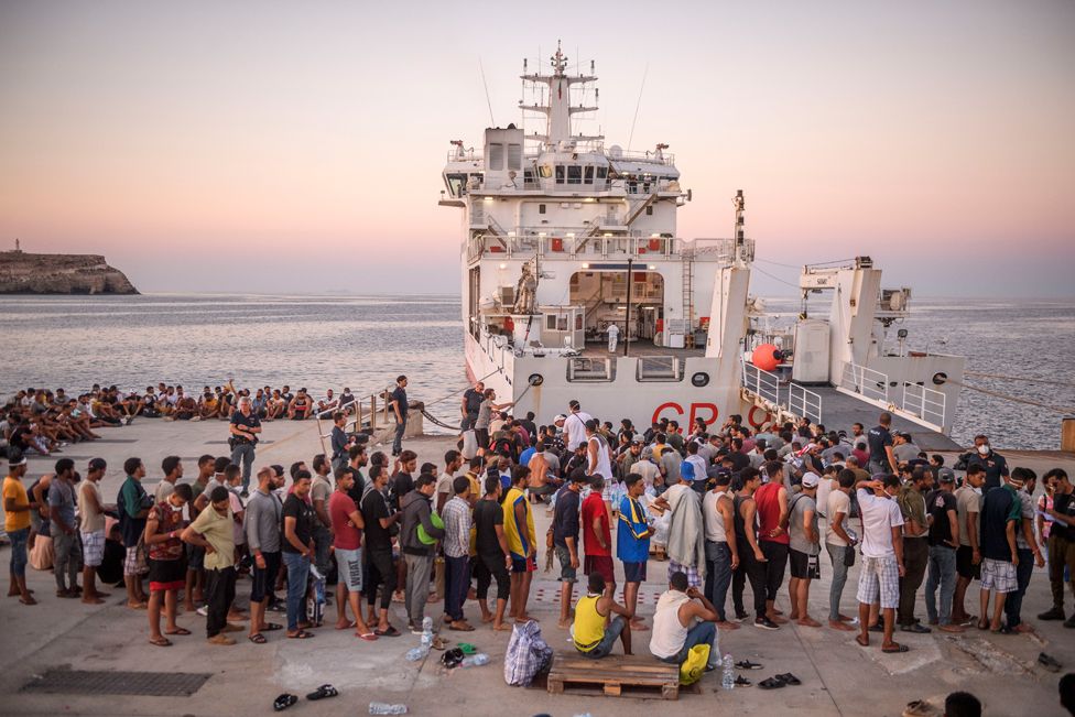 Migrants wait to board a coast guard ship in Lampedusa for transfer to Porto Empedocle, Sicily, Italy.