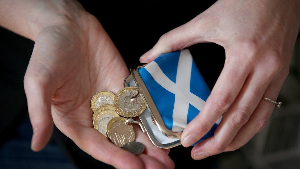 Pounds coins being tipped out of a purse with the flag of Scotland