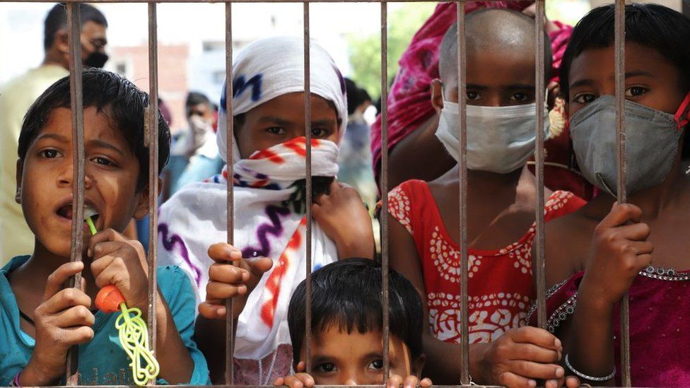 Дети в трущобах в Гуруграме носят маски в качестве меры предосторожности в связи с распространением нового коронавируса COVID-19 на окраинах Нью-Дели, Индия, 24 апреля 2020 года.