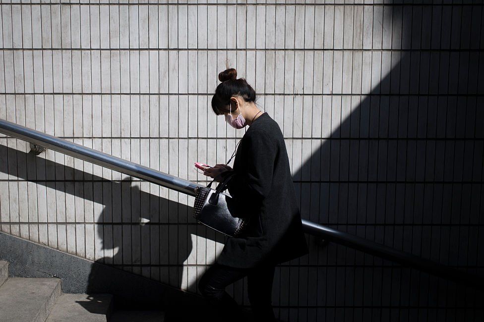 A woman walks as she reads her text on her phone in Beijing, on 23 March 2016.