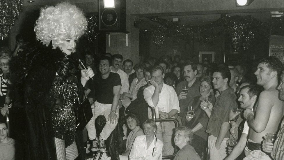 Black and white photograph of Lily Savage performing for a packed crowd at Manhattans first birthday (28 November 1990)