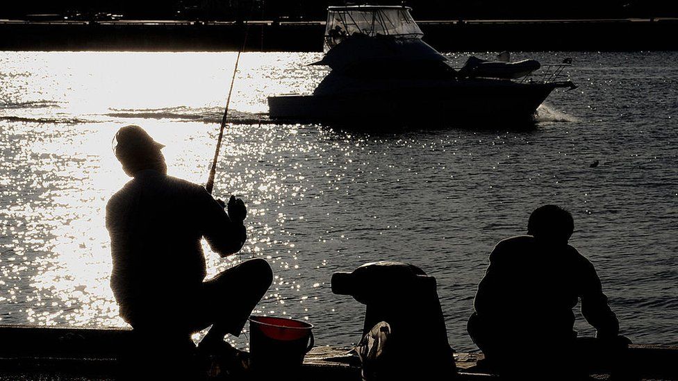 Fisherman sit and fish from the wharf of a Western Australian harbour
