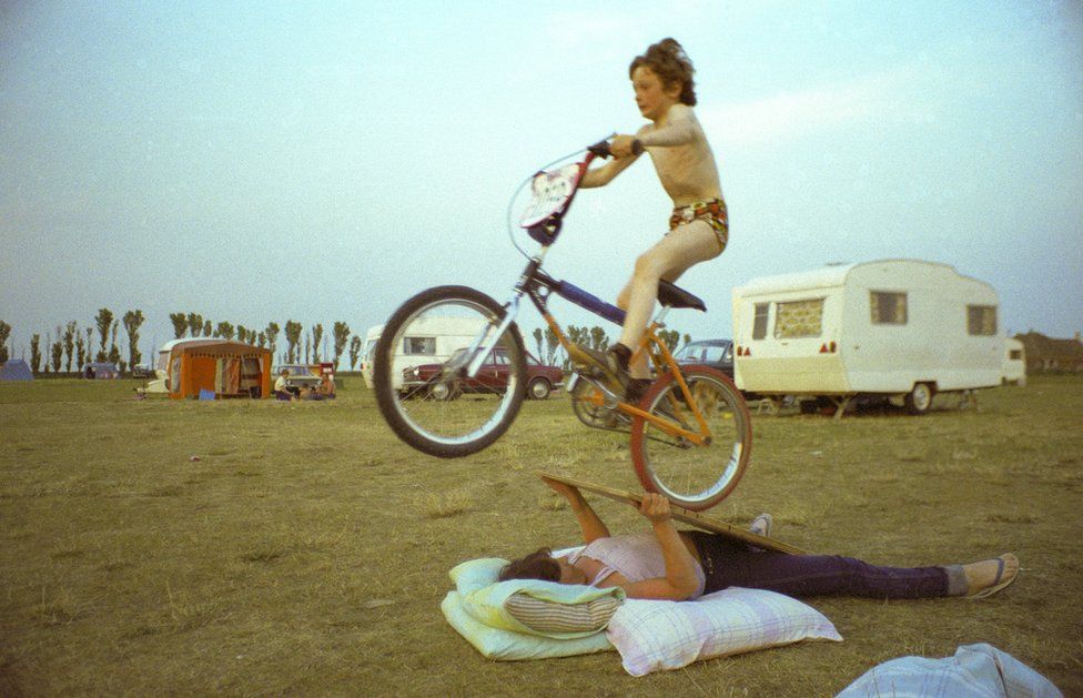 woman lies down and lifts a ramp, which her son ride over