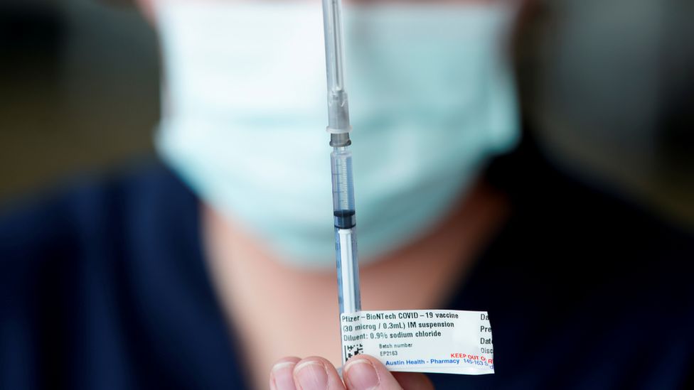 Медицинский работник держит иглу с вакциной Pfizer