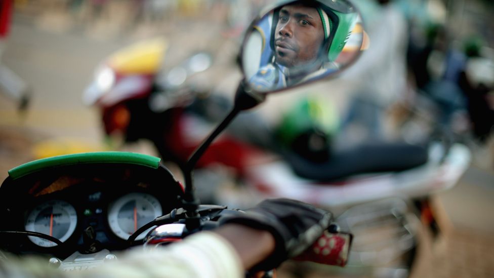 Motorcycle taxi driver reflected in wing mirror in Kigali, Rwanda