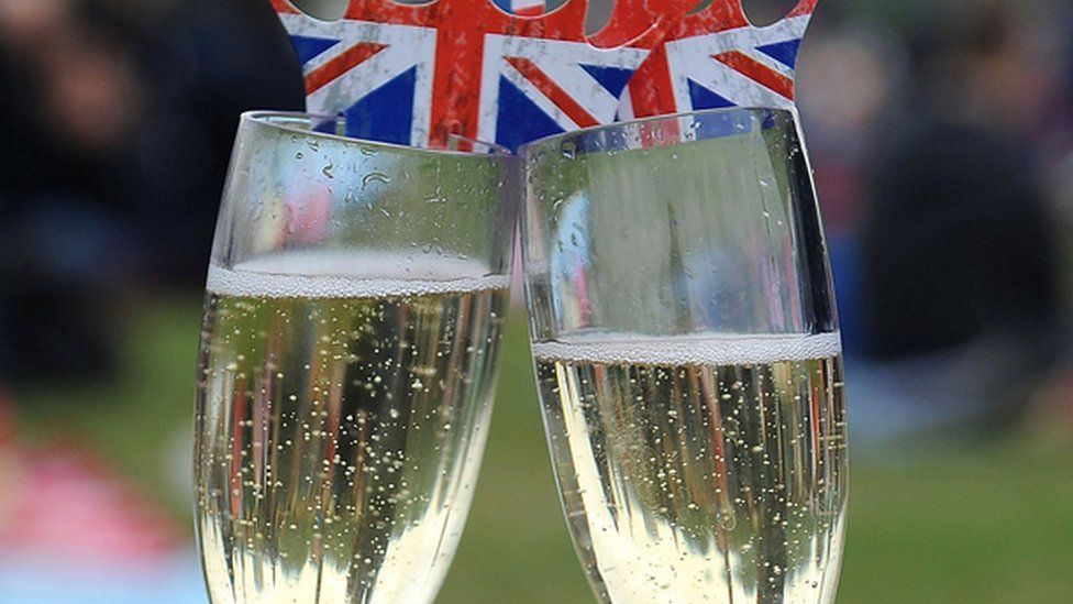 Two sparkling wine glasses with British flag "crowns" on top