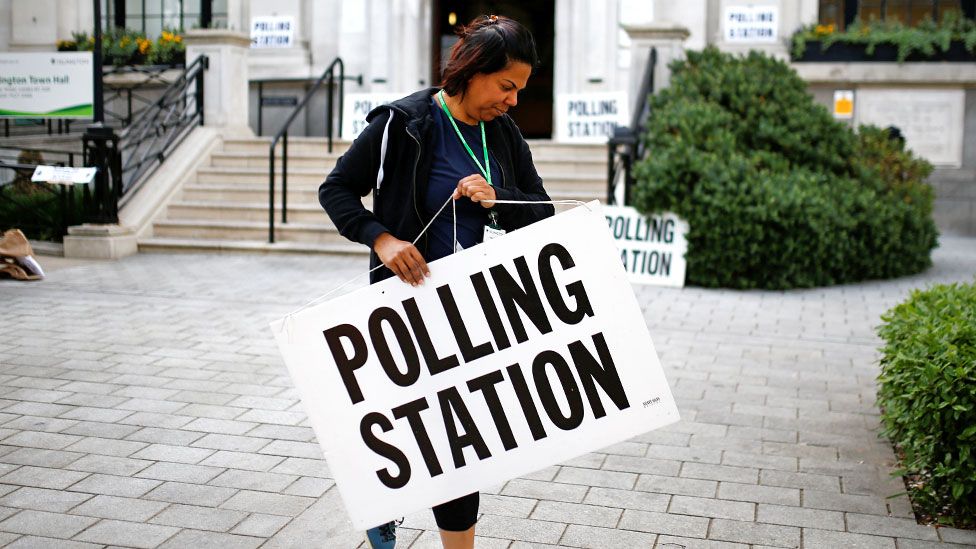 An electoral staff member places a sign outside a polling station for the European elections