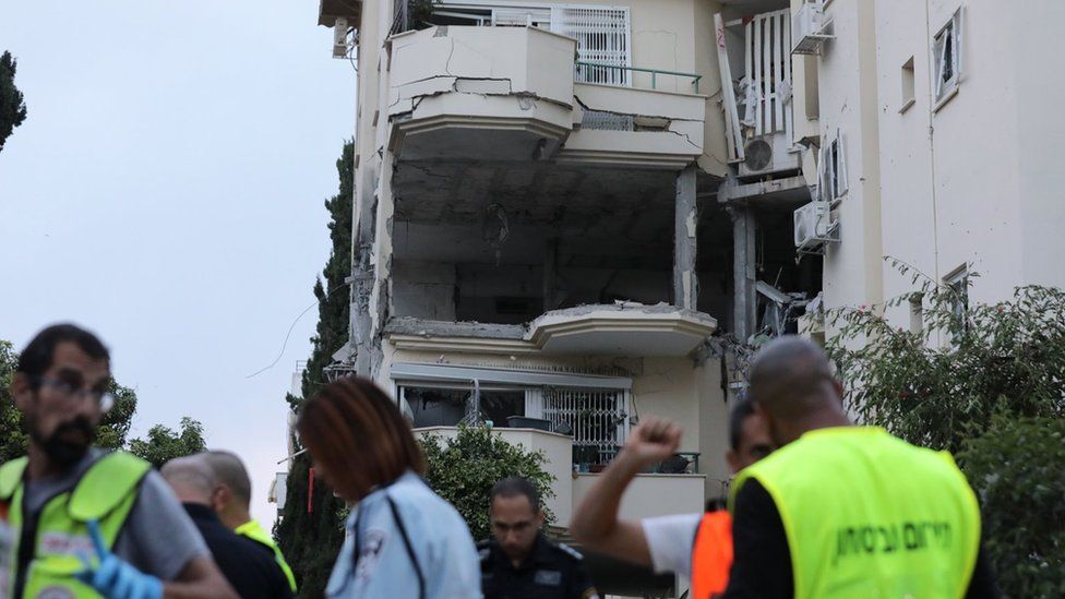 Israeli emergency services personnel work next to an apartment building in the Israeli city of Rehovot that was hit by a Palestinian rocket fired from the Gaza Strip, killing an elderly Israeli woman (11 May 2023)