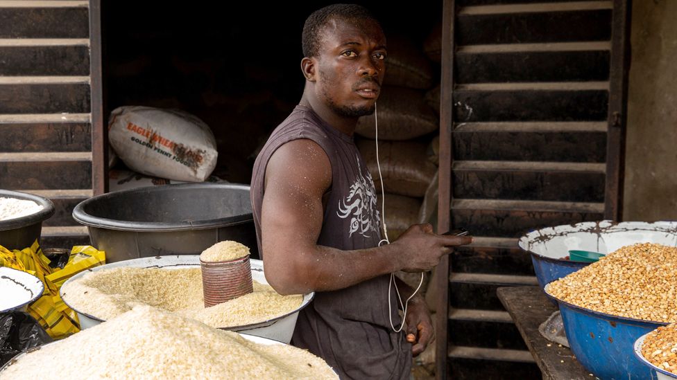 A Nigerian man poses next to some rice in his shop at Ajara Market in Badagry, near Lagos, on 6 September 2019