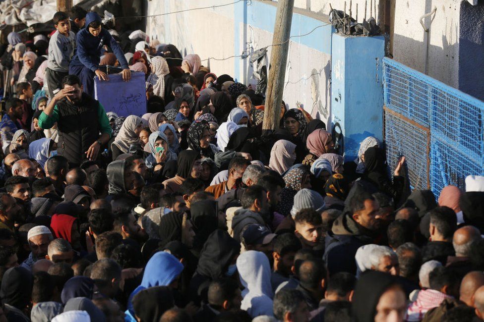 Palestinians line up for flour being distributed by the UN agency for Palestinian refugees (UNRWA) in Deir Al Balah, Gaza on 7 December, 2023