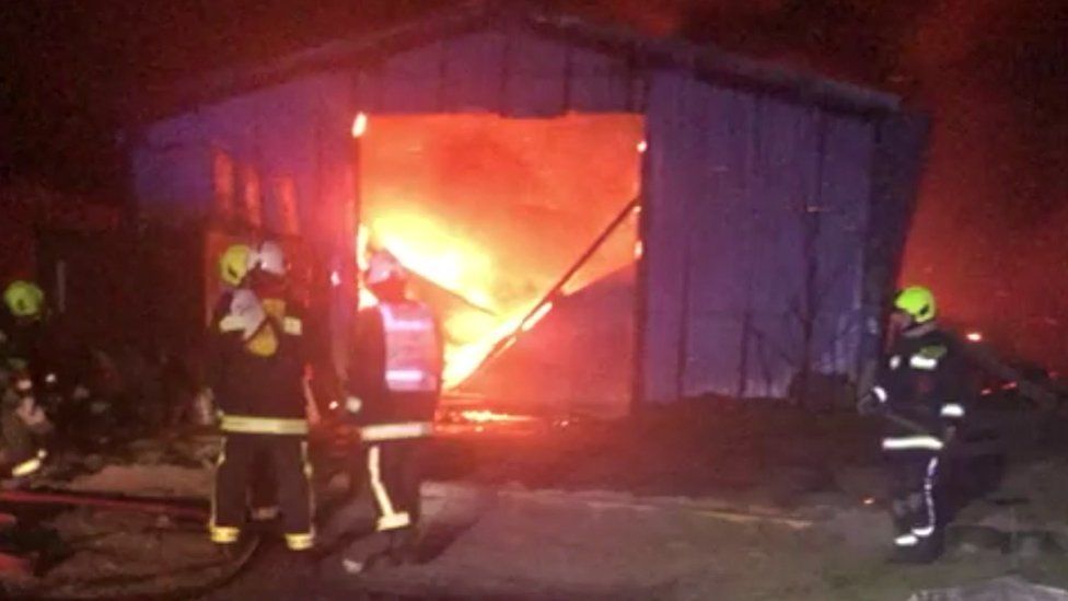 Barn on fire with firefighters in front