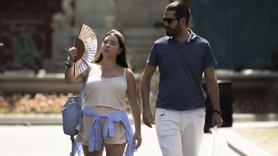 A woman, using a fan, is seen as heatwave hits London