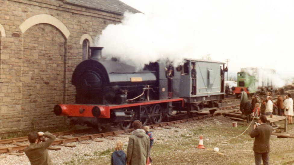 Steam locomotive attached to a wagon with steam blowing