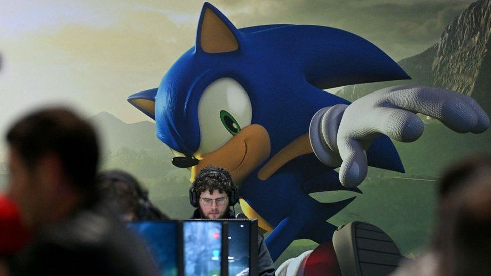 Gamers play in front of a huge mural of Sonic The Hedgehog at Paris Games Week in 2022.