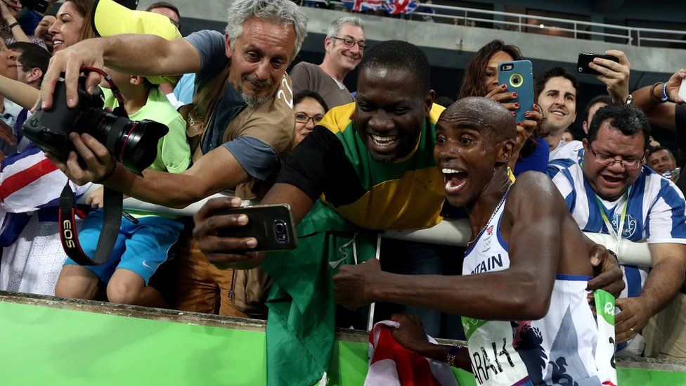 Mo Farah poses for a selfie with a fan after winning the 5,000m.