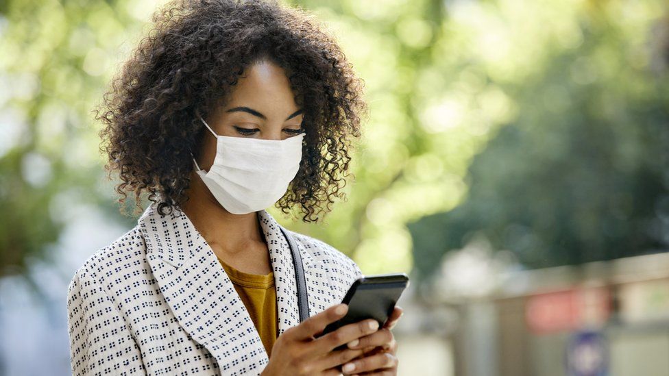 woman wearing mask looks at phone