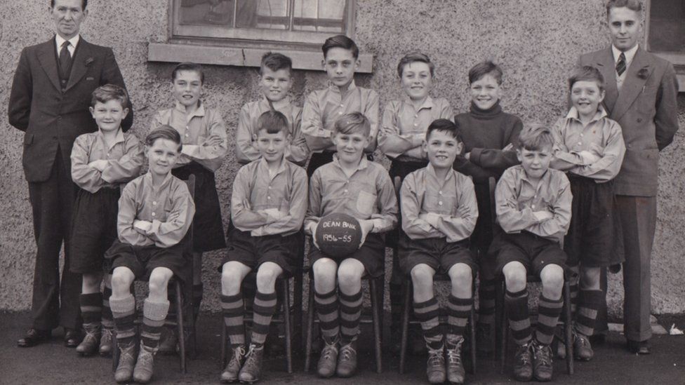 Old black and white picture of young footballer players posing in rows