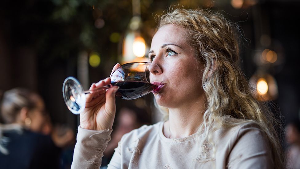 Woman drinking glass of wine in pub