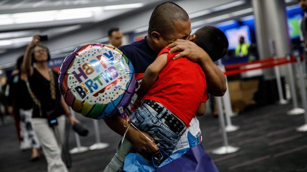 Un padre se reencuentra con su hijo en el aeropuerto, lo carga y llora.