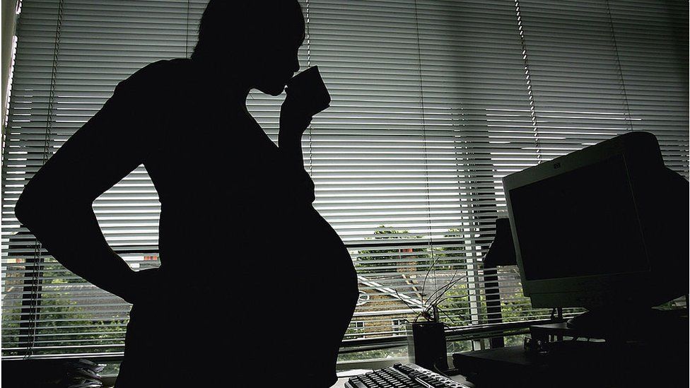 A pregnant woman looking at a computer