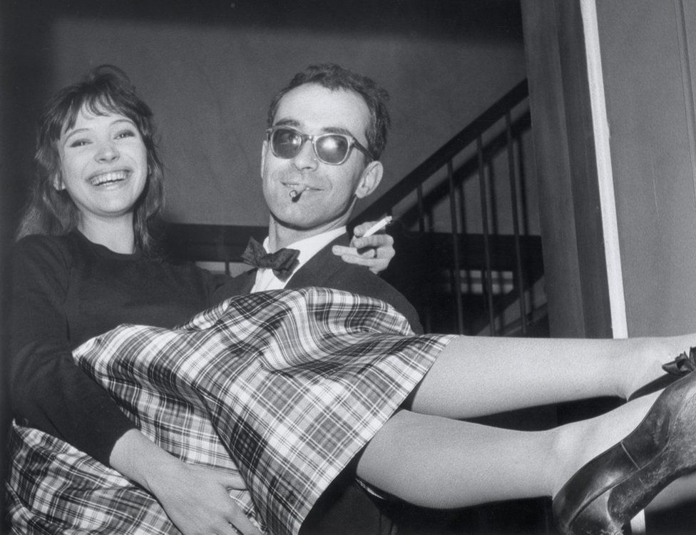 An archive photo of Jean-Luc Godard carrying Anna Karina while the two of them laugh