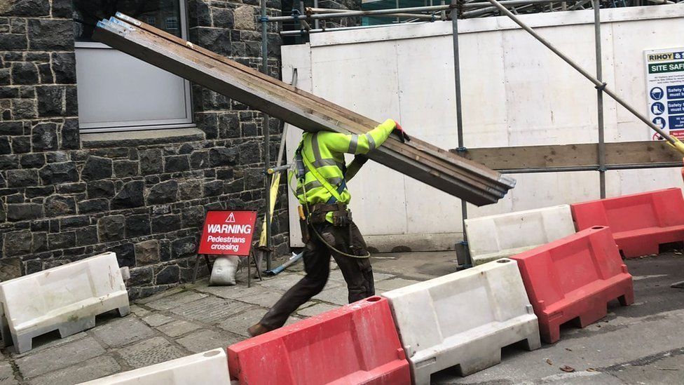 Worker carrying scaffold planks on a building site