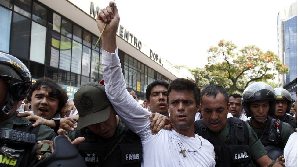 Leopoldo Lopez, dressed in white and holding a flower, is taken into custody by Bolivarian National Guards in Caracas, Venezuela, 18 February 2014