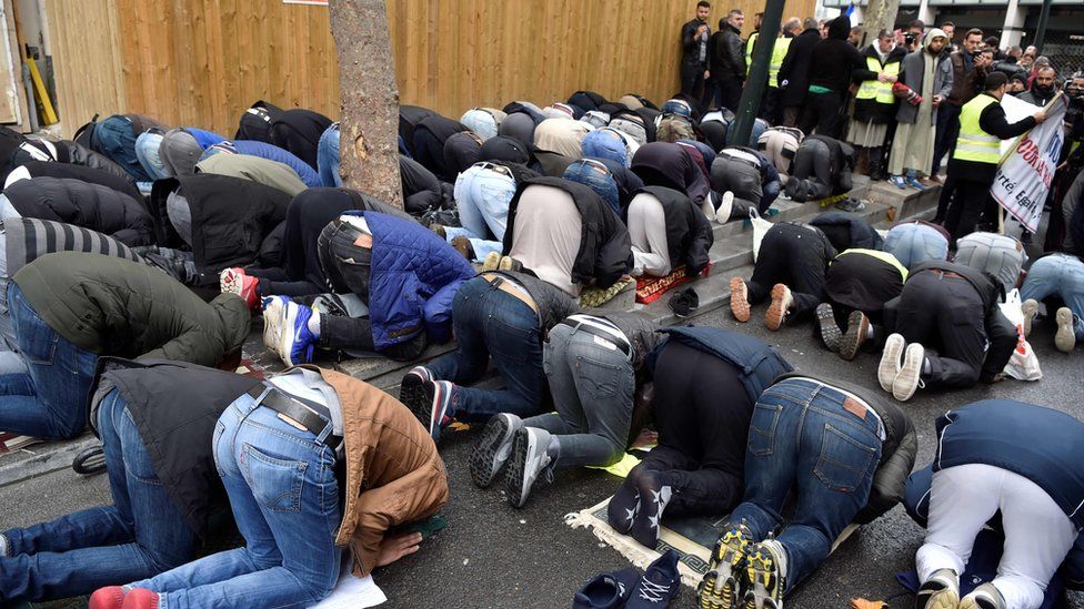 People pray in a street on November, 10, 2017, in Clichy, near Paris,