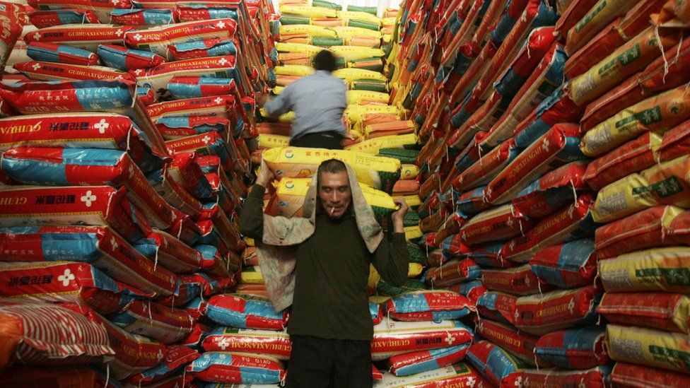 A man carries bags of rice in a warehouse in China.
