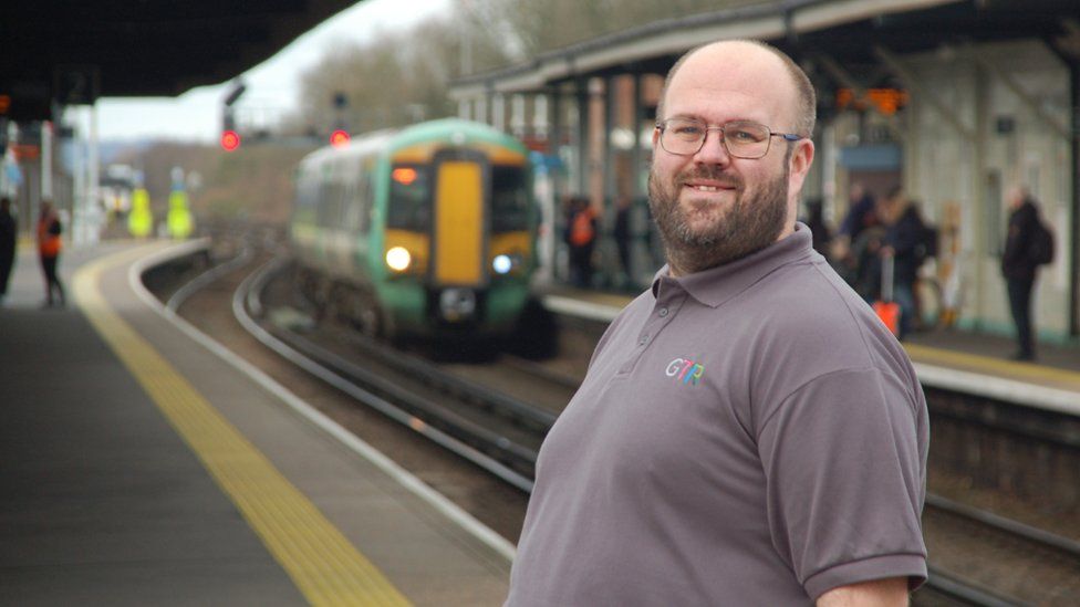 Dave Jones at a station with a train passing in the background