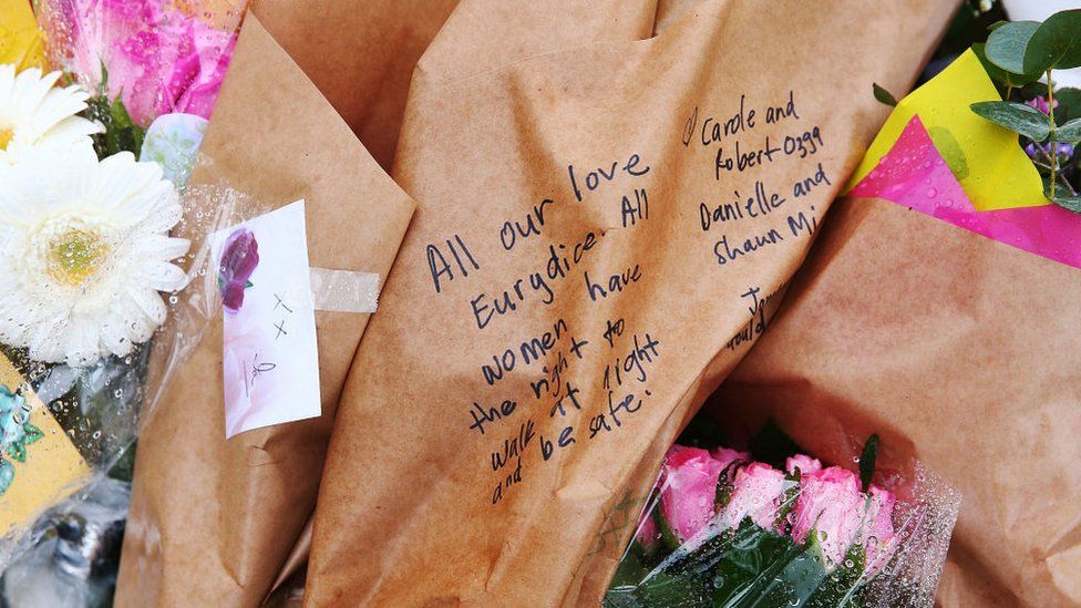 A message on a bouquet tribute reads: "All our love Eurydice. All women have the right to walk at night and be safe."