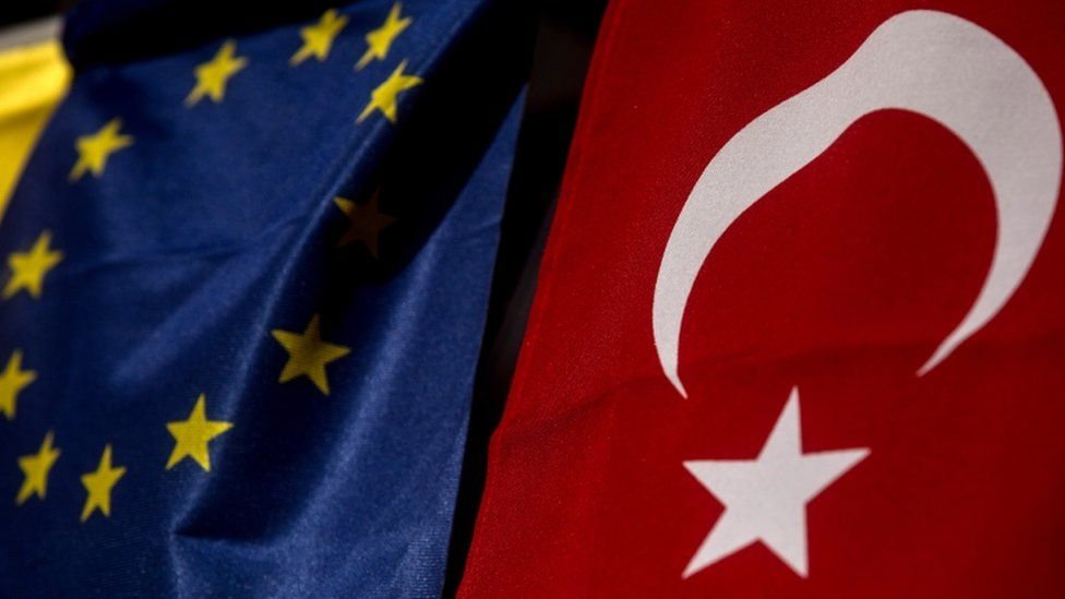 Turkish flag hands next to EU flag