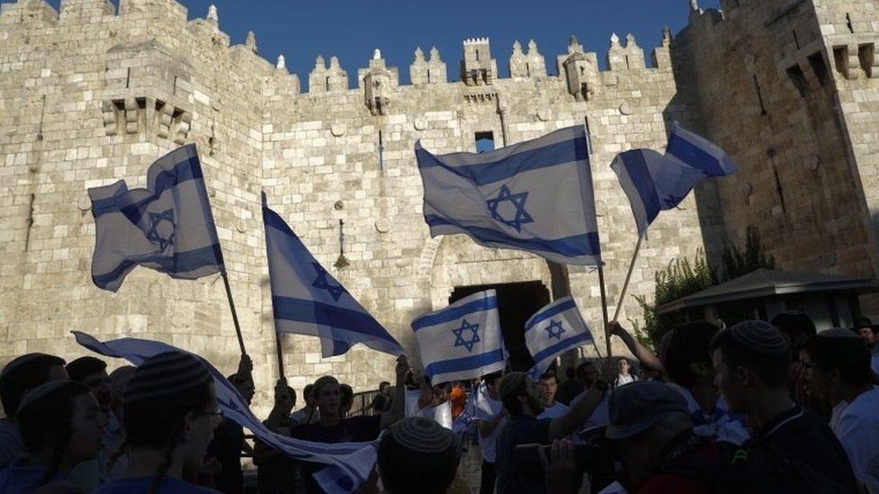 Israeli nationalists wave Israeli flags outside the Damascus Gate of Jerusalem's Old City (15 June 2021)