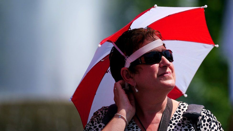 A woman wears an umbrella hat for shade in Trafalgar Square