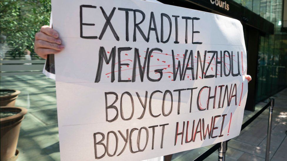 A protester holds up a sign outside British Columbia Supreme Court where Meng Wanzhou attended a hearing on May 27, 2020 in Vancouver, Canad