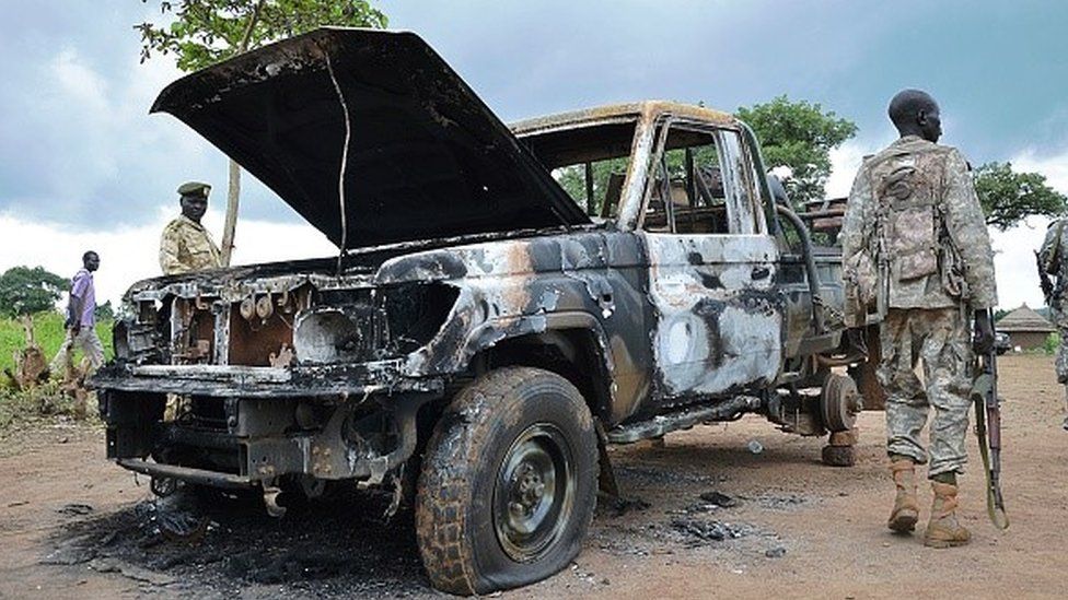 South Sudanese SPLA soldiers inspect a burned out car in Pageri in Eastern Equatoria state on August 20, 2015