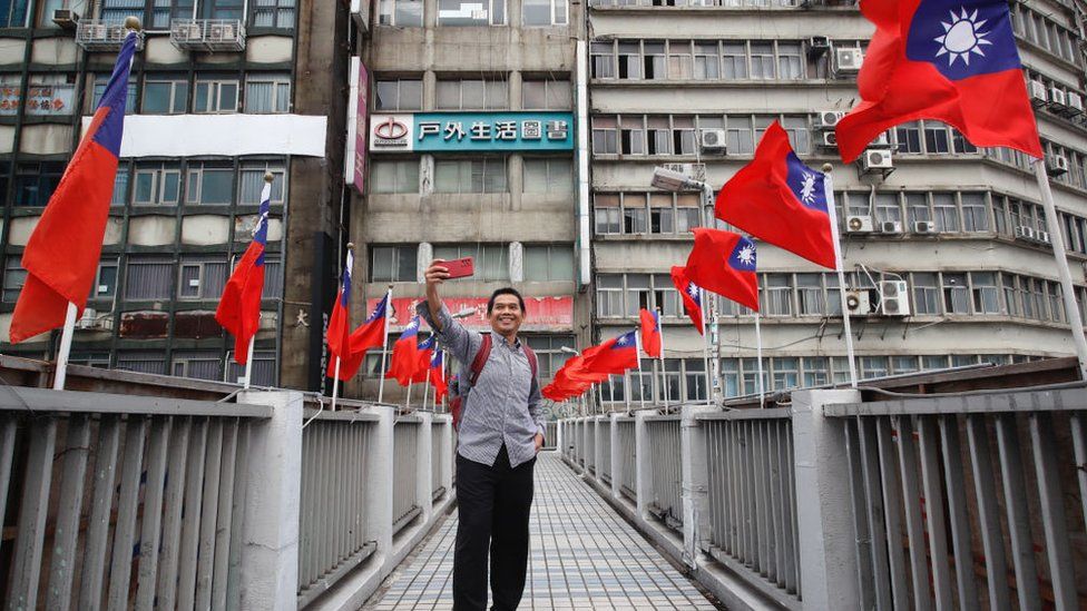 An Indonesian visitor takes selfies on a footbridge in Taipei, where Taiwan flags flutter ahead of the islands national day, amid rising tensions with China, in Taipei, Taiwan,